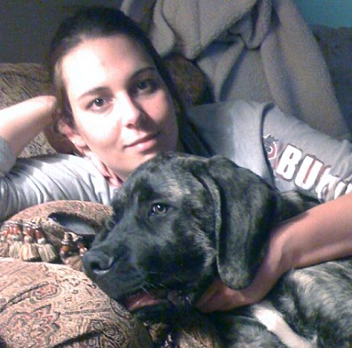 A woman holding a black dog named Duke