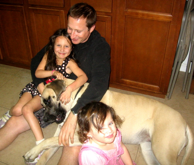 A man and his daughters playing with a dog