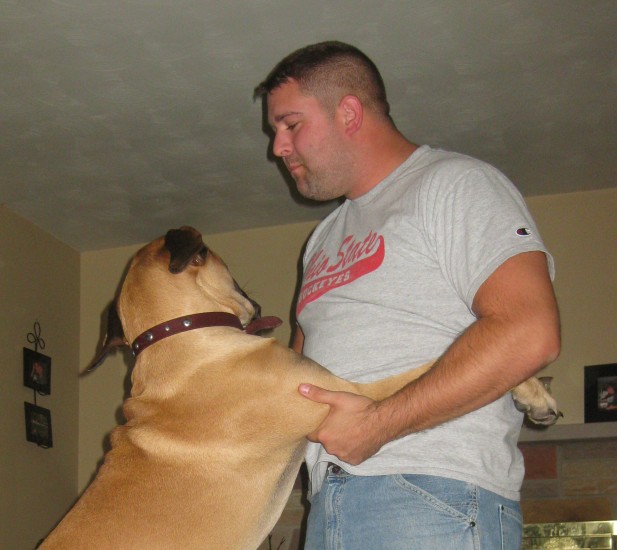 A man wearing a grey shirt dancing with a dog